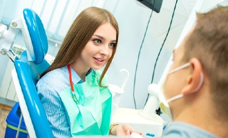 A young female talks to her dentist about the possibility of her CEREC crown being covered by dental insurance