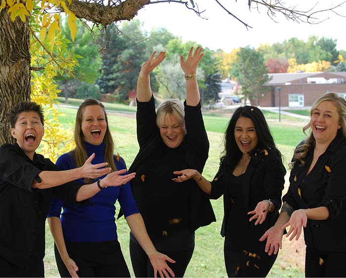 Team members smiling posing by tree