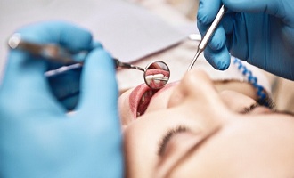Close-up of dentist using mirror to examine patient’s teeth