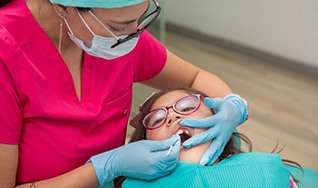 Dental team member applying fluoride to child’s teeth