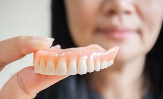 Woman holding her upper denture 