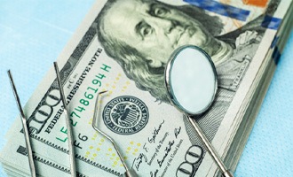  dental instruments sitting atop a stack of money