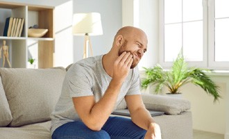  a person holding their mouth while sitting on a couch