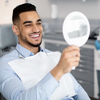 Male patient looking at brighter smile in the mirror