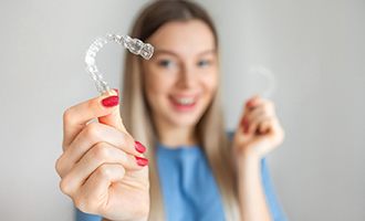 Young woman holding Invisalign and smiling