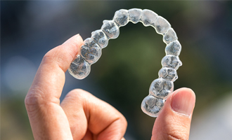 Someone holding up a clear aligner tray 