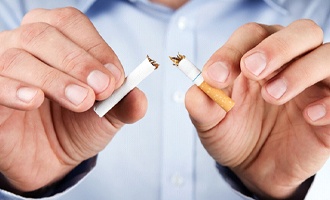 Man breaking cigarette in half to prevent oral cancer