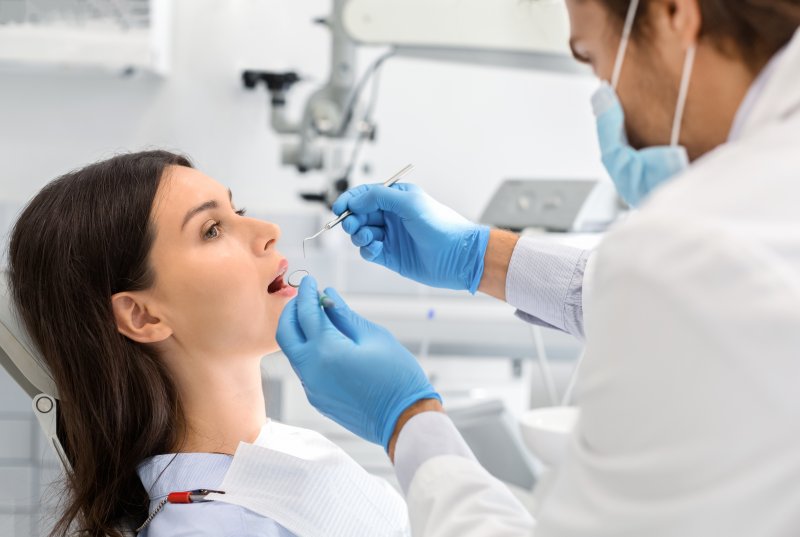 a woman sitting in the dentist’s chair while her dentist performs a checkup