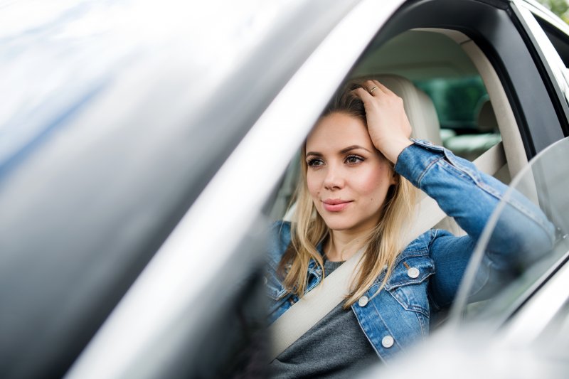 a woman sitting in her vehicle while waiting for her dentist’s appointment