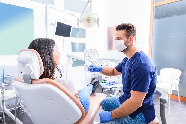 a male dentist prepares to clean a female patient’s teeth and gums 