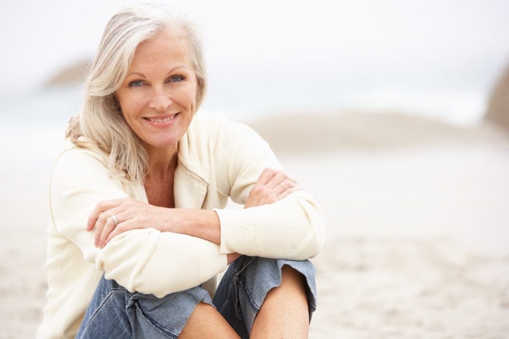 Woman with implant dentures smiling on beach