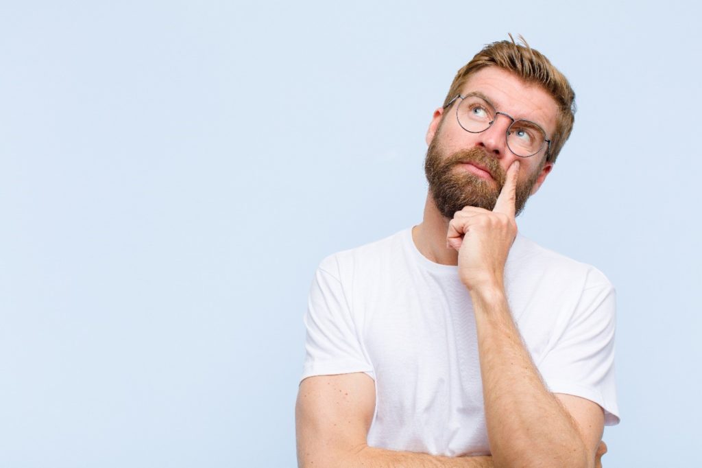 Closeup of man with beard and glasses wondering