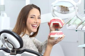 a closeup of a patient holding a model of dentures