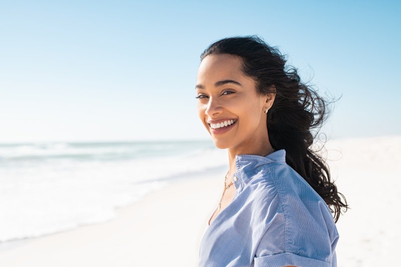 woman walking on the beach and smiling with veneers