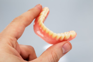 a closeup of a patient holding their lower denture