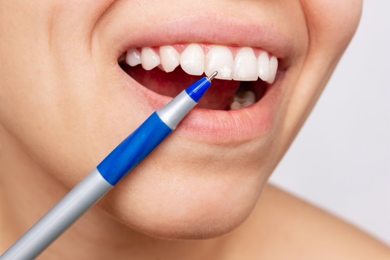 up-close image of person pointing to white spot on tooth