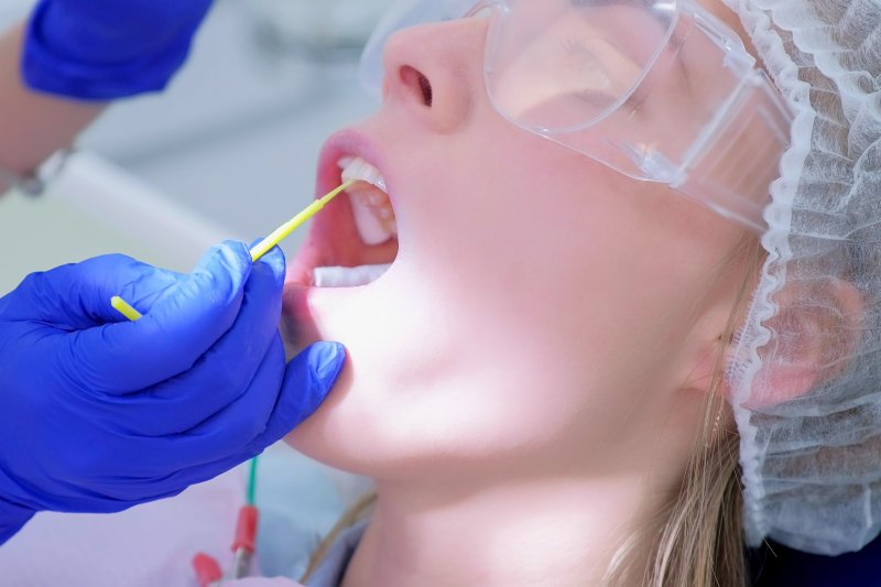 dentist applying fluoride to the patient’s smile